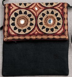 a black purse with an intricate design on the front and side, sitting on top of a gray surface