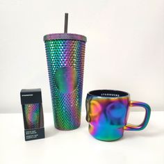 a rainbow colored coffee cup next to a black box