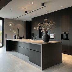 a vase with flowers is sitting on a counter in the middle of a large kitchen