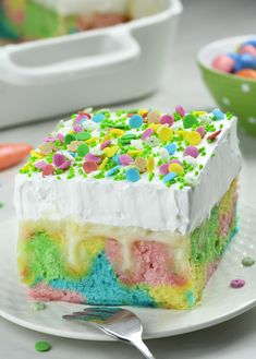 a slice of rainbow cake with white frosting and sprinkles