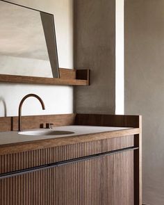 a bathroom sink sitting under a mirror next to a wooden counter top with a faucet