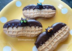 three waffles with chocolate frosting and spooky eyes are on a yellow plate