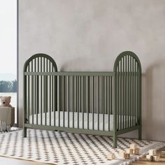 a baby crib next to a teddy bear in a room with a checkered rug