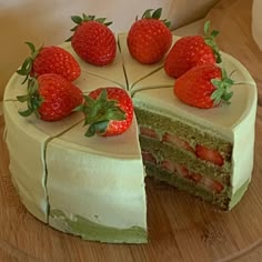 a cake with white frosting and strawberries on top is cut in half to show the inside