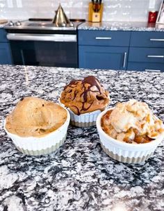 three cupcakes sitting on top of a kitchen counter