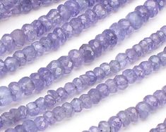 purple glass beads are lined up on a white surface