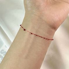 a woman's arm with a red beaded bracelet on it