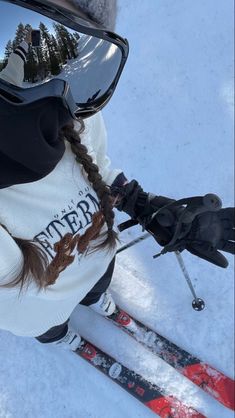 a woman in white jacket on skis next to poles and snowboarder's goggles