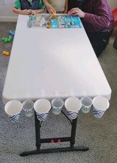 an older man and young boy are sitting at a table with cups on it,