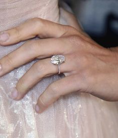 a close up of a person's hand with a diamond ring on their finger