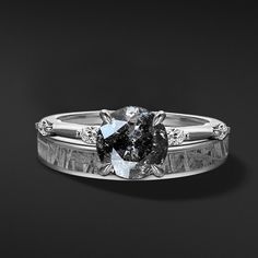 an engagement ring with a black diamond in the center and two white diamonds on each side