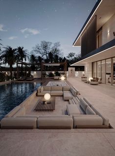 an outdoor living area with couches and tables next to a swimming pool at night