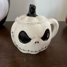 a ceramic teapot with a face painted on the front and side, sitting on a table