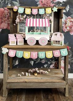 a birthday cake stand in front of a floral wallpapered background with pink and green flowers