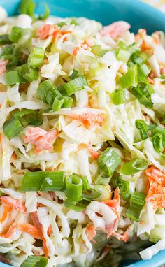 a blue bowl filled with coleslaw and carrots on top of a table