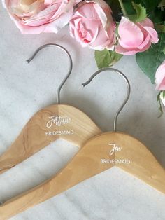 two wooden hangers with names on them next to pink roses