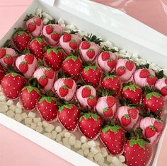 a box filled with lots of pink and red strawberries next to white chocolate hearts