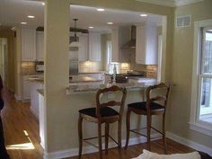 a kitchen with two stools in front of the counter and an open floor plan