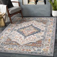 a large rug with an ornate design on the floor in front of a chair and bookshelf