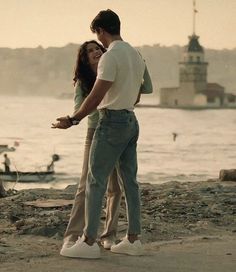 a man and woman standing next to each other near the water