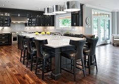 a large open concept kitchen and dining room with hardwood floors, black cabinets and white counter tops