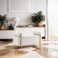 a living room with white furniture and potted plants on the sideboard next to it