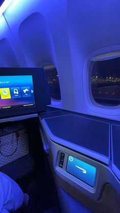 the inside of an airplane with blue lights on it's windows and entertainment screen