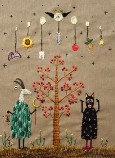 an embroidered wall hanging with two cats and a tree in the middle, surrounded by other items