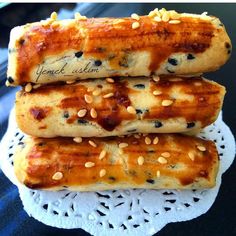 three pieces of bread with sesame seeds and sauce on them sitting on a doily