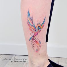 a colorful bird tattoo on the right leg, with watercolors and inking