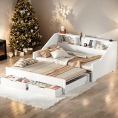 a white bed sitting on top of a wooden floor next to a christmas tree