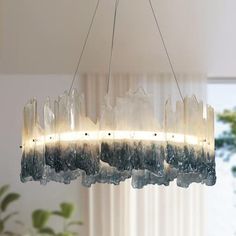 a chandelier hanging from a ceiling in a room with white walls and curtains