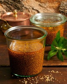 two jars filled with food sitting on top of a wooden table next to a plant