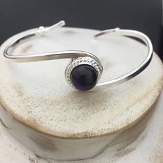 A simplistic and elegant sterling silver bracelet cuff, with an 8mm gemstone cabochon of your choosing in the drop down menu! This is shown with a few different stone colors and I can accommodate if preferred. Also, when ordering, please tell me your wrist size so I can have this fit you perfectly! Shipping is First Class with Delivery Confirmation, within the US, and First Class International outside. *SIZING GUIDE* Take a snug wrist measurement and add 1 inch to determine which size to order. Silver Sterling Silver Cuff Bracelet With Cabochon, Sterling Silver Bangle With Gemstone, Adjustable Sterling Silver Cuff Bracelet With Cabochon, Adjustable Sterling Silver Cabochon Cuff Bracelet, Adjustable Cabochon Sterling Silver Cuff Bracelet, Elegant Silver Amethyst Cuff Bracelet, Elegant Silver Amethyst Bangle, Elegant Sterling Silver Bracelet With Cabochon, Silver Amethyst Gemstone Cuff Bracelet