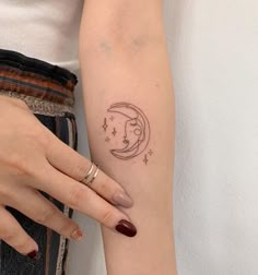 a woman's left arm with a small tattoo on it, which has the moon and stars