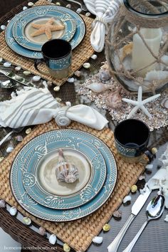 the table is set with blue and white plates, silverware, and starfish