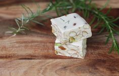 two pieces of white soap sitting on top of a wooden table next to green leaves