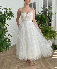 a woman wearing a white dress with polka dots on it and flowers in her hair