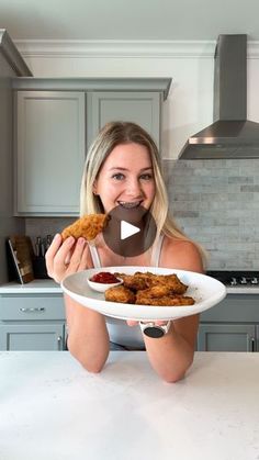 a woman sitting at a kitchen table with a plate of food in front of her