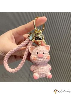 a hand holding a pink keychain with a pig on it