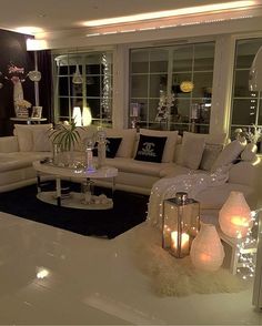 a living room filled with lots of white furniture and candles on top of the tables