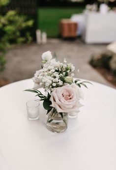 a vase filled with flowers sitting on top of a table next to two shot glasses