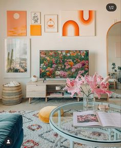 a living room filled with furniture and art on the wall above a glass coffee table