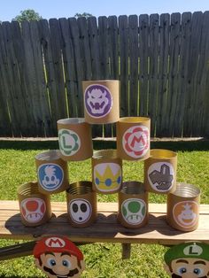 some paper cups that have mario and luigi's faces on them in front of a fence