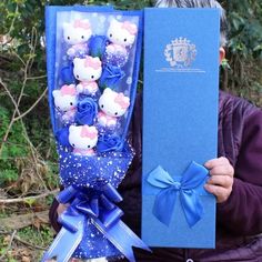 a man holding a blue box with hello kitty stuffed animals in it's lap