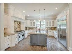 a large kitchen with white cabinets and marble counter tops