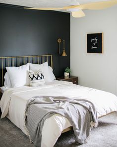 a bedroom with black walls and white bedding