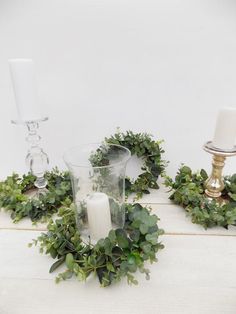 candles and greenery are arranged on a table