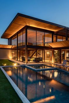 a modern house with a pool in the yard at night, lit up by lights