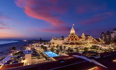 the hotel is lit up at night by the ocean and beach side with its lights on